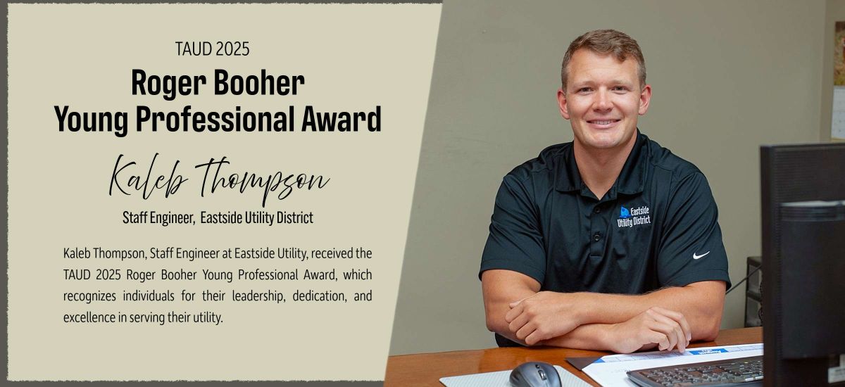 Picture of Kaleb Thompson at his desk with the award on wall. 